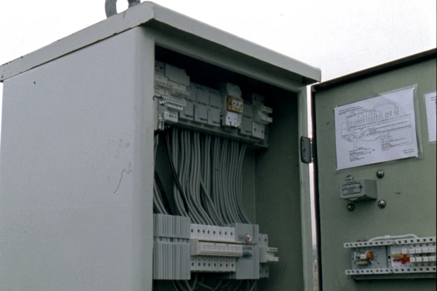An open field instrument cabinet on a plant in daylight: terminal blocks, marshalling cables and isolators on a DIN rail.
