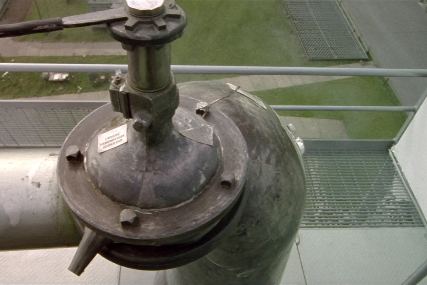 A pressure safety valve on top of a process vessel in daylight, its outlet rising away, a lead seal on the adjusting cap.